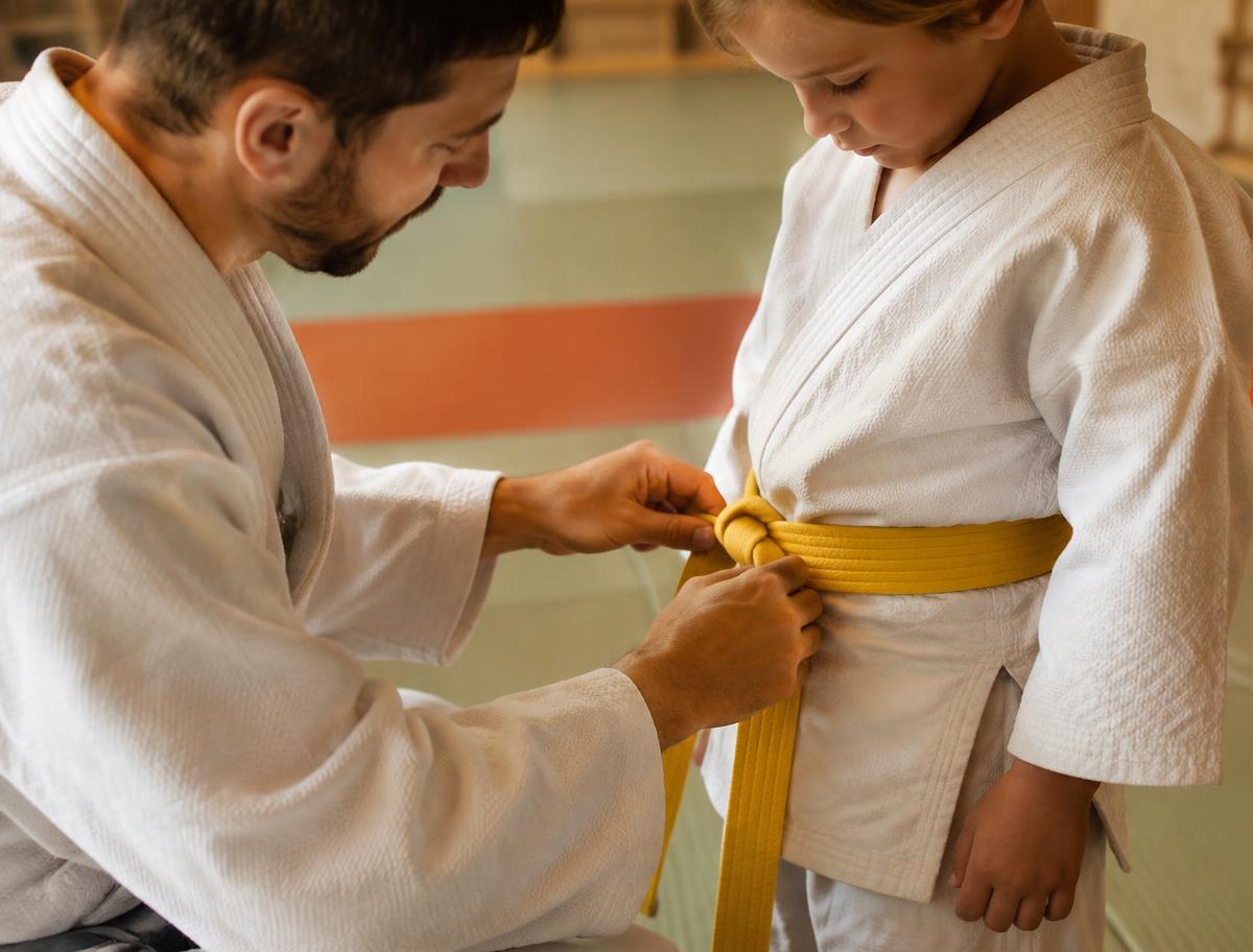 Un professeur noue la ceinture d'un enfant